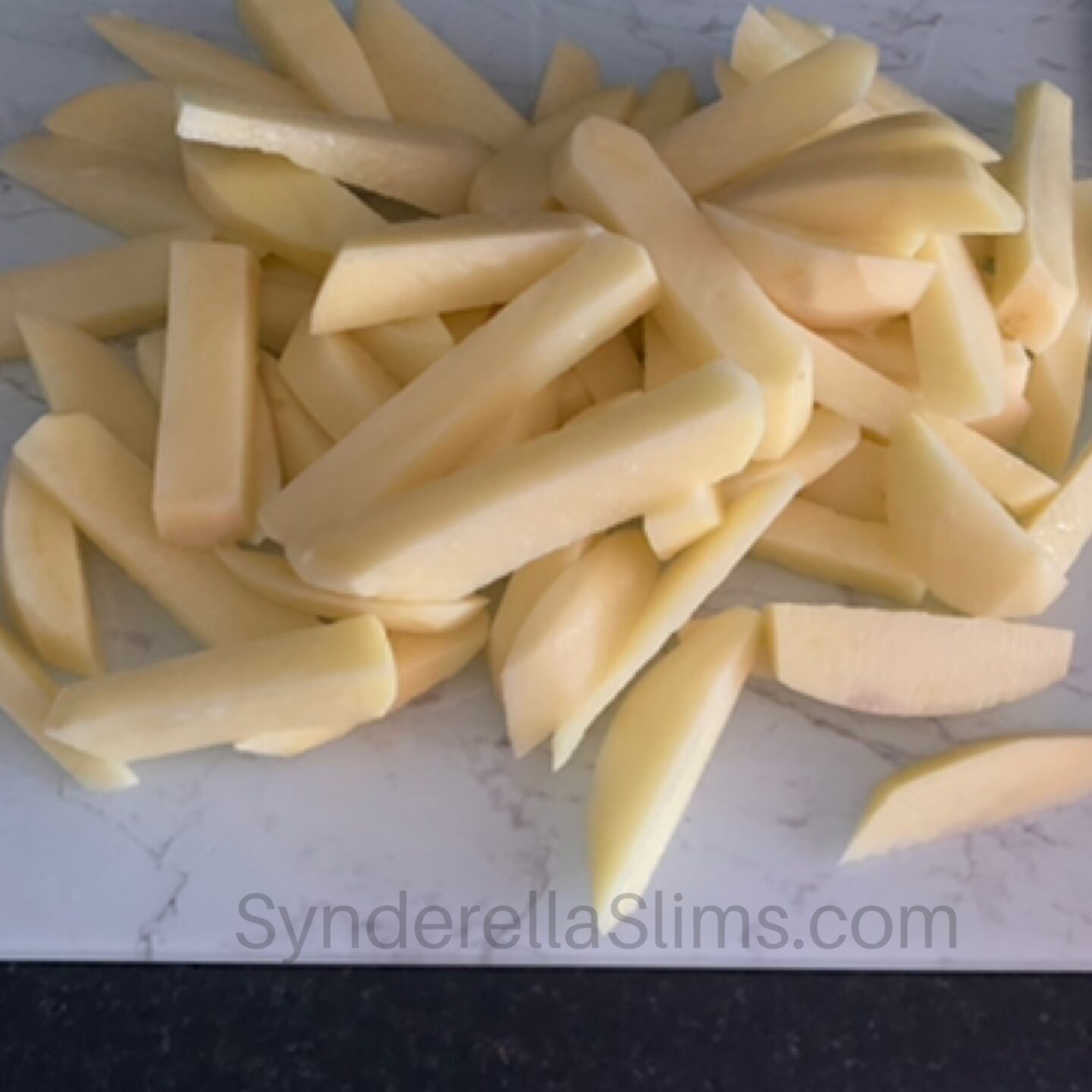 a pile of skinned and chopped potatoes on a chopping board